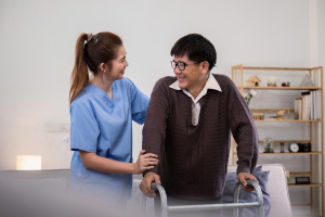 care at home after hospital caregiver assisting elderly man with mobility using walking frame