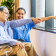 An Asian nurse comforting an elderly patient in a wheelchair, illustrating what is dementia training awareness in professional senior care facilities.