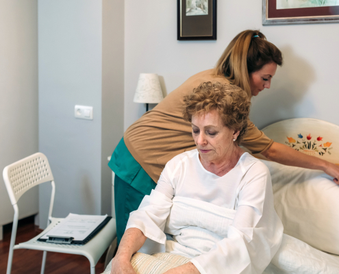 Caregiver accommodating pillow to elderly patient and providing elderly care at home