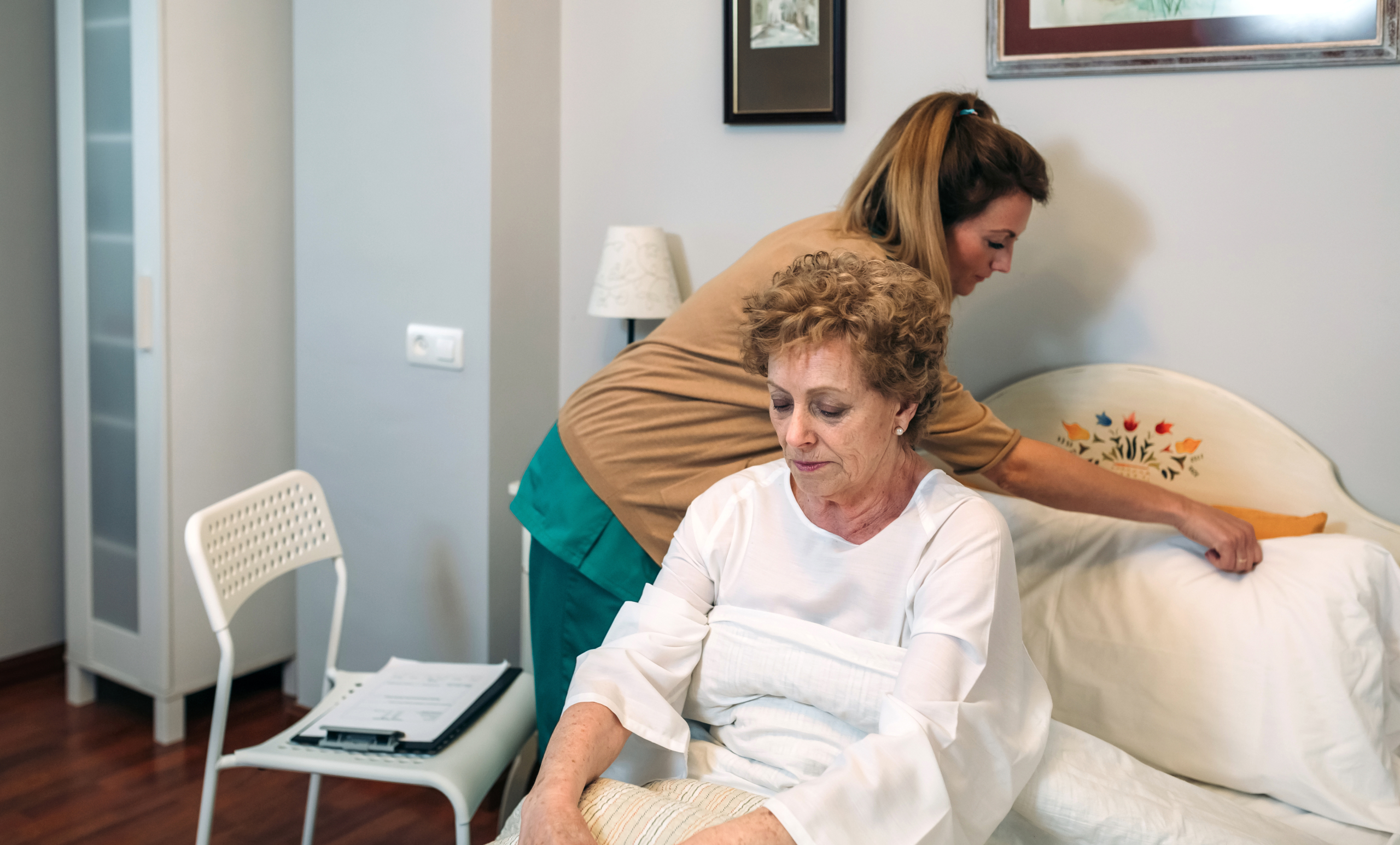 Caregiver accommodating pillow to elderly patient and providing elderly care at home Caregiver accommodating pillow to elderly patient and providing elderly care at home