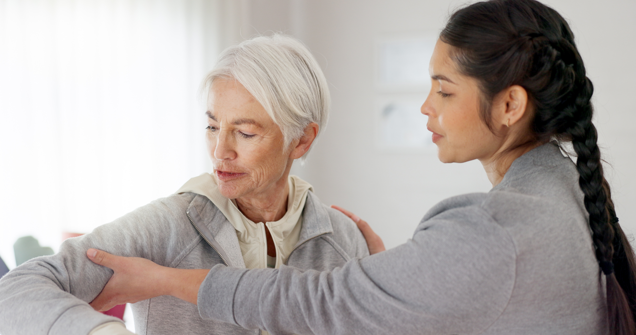 A carer gently assisting an older person, reflecting the hands-on support of middle stage dementia care