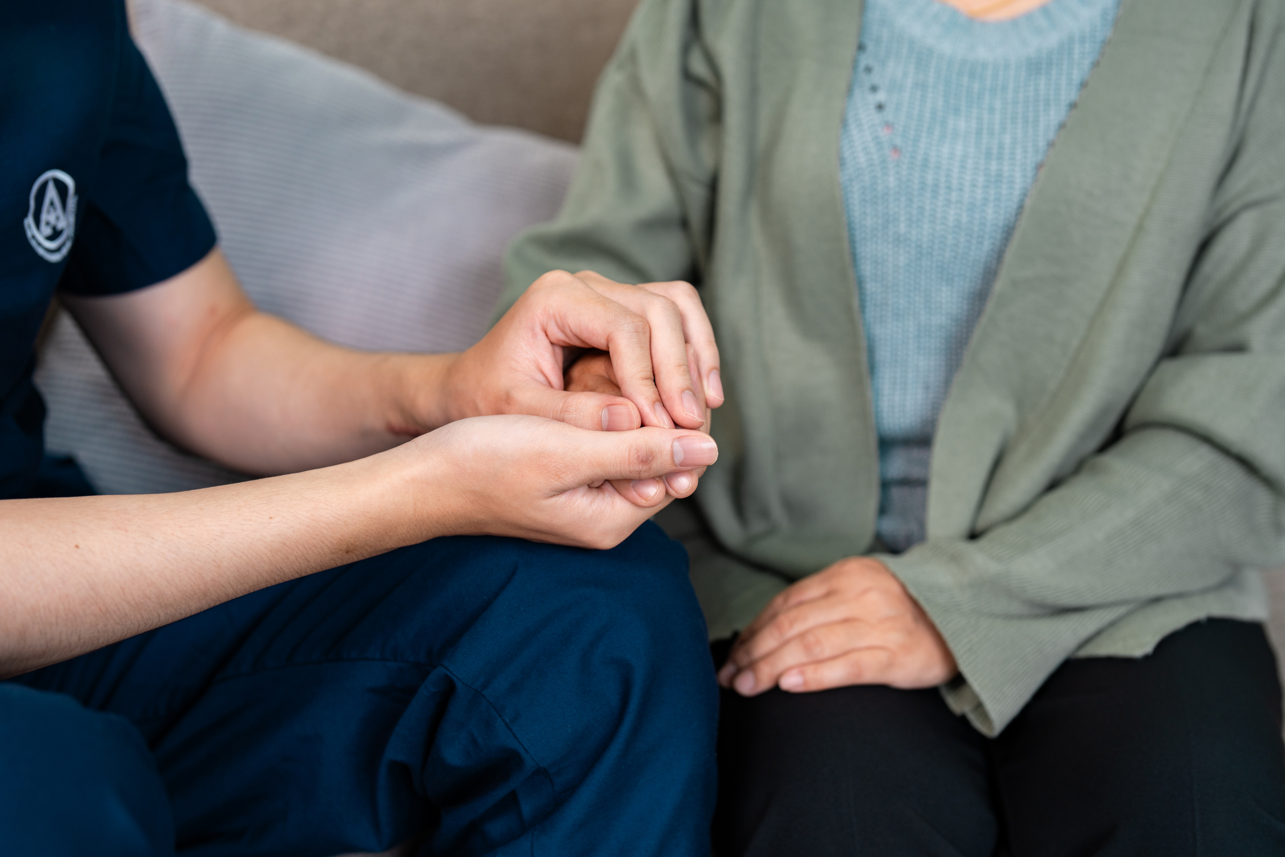 Compassionate healthcare provider holding elderly patient's hand during an emotional support session carer-holding-hand-late-stage-dementia-care.jpg