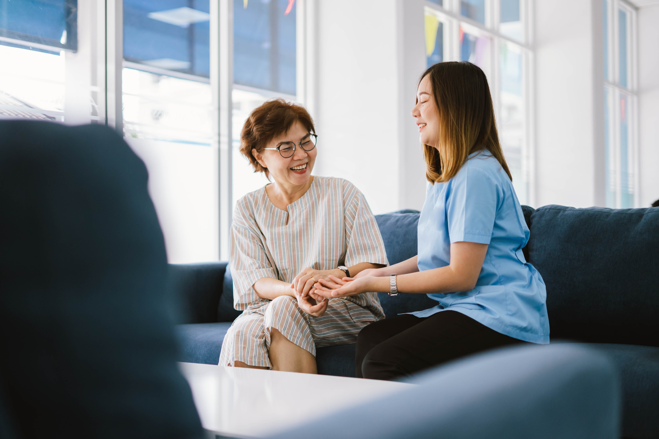 Trained carer using dementia communication training techniques to connect gently with an elderly woman at home
