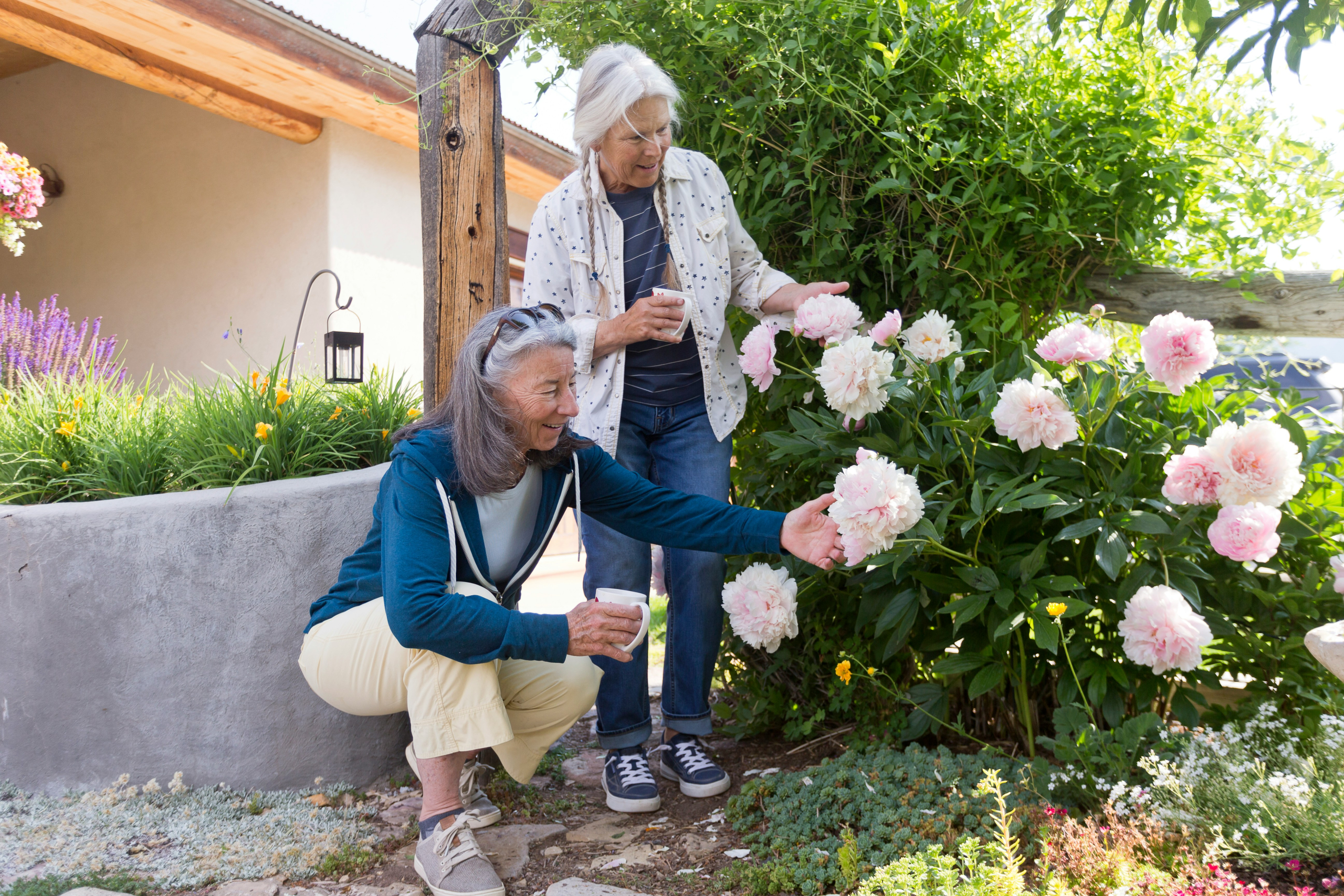 Two older women admiring garden flowers, holistic wellbeing